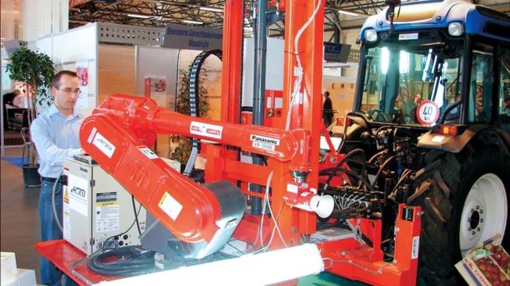 Robotic apple picker mounted on a tractor using machine vision for automated fruit harvesting.