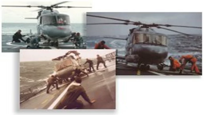 Manual handling of a helicopter on a ship deck under rough sea conditions.