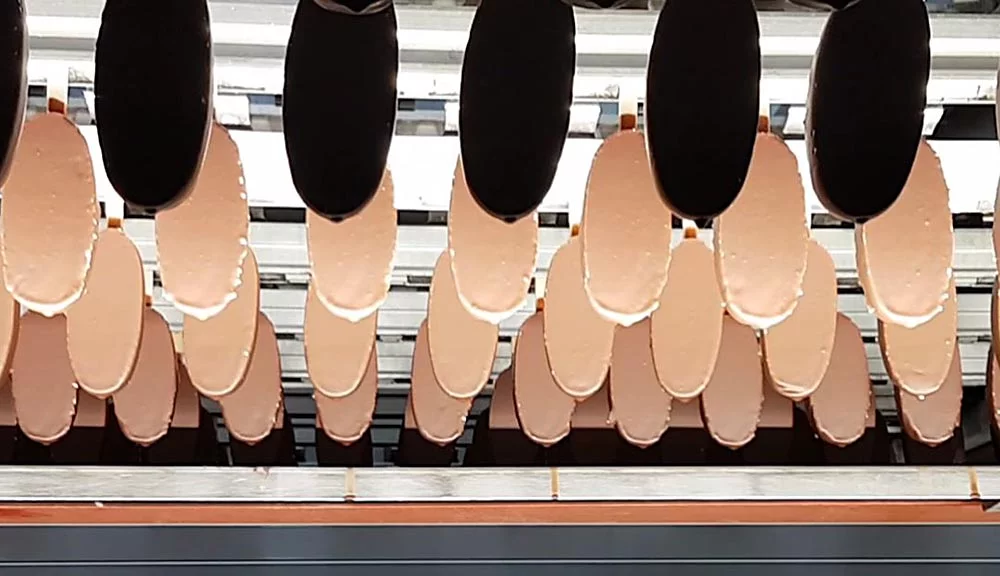 Ice creams transported on a conveyor system during automated food production.