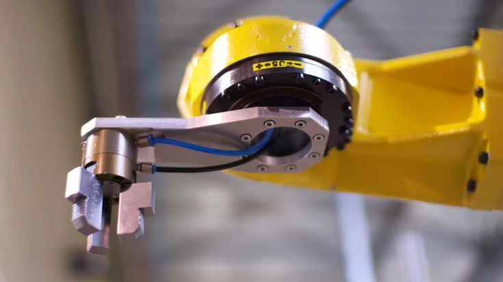 Robot arm in a flexible manufacturing cell used for automotive parts inspection and assembly with vision-guided system.