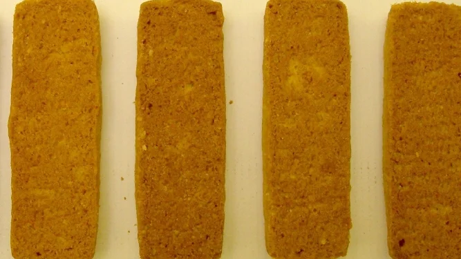 Biscuits arranged on a conveyor belt for automated size and dimension inspection using machine vision.