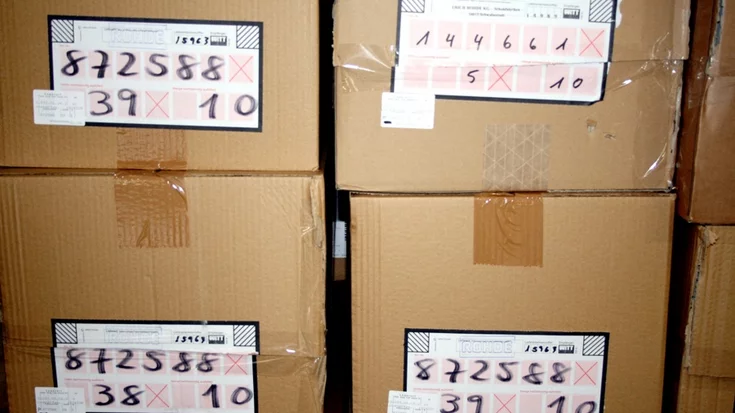 Packages with handwritten labels used for OCR-based identification in a warehouse logistics system.