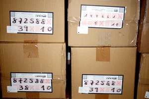 Packages with handwritten labels used for OCR-based identification in a warehouse logistics system.