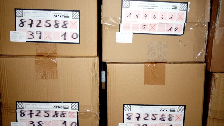 Packages with handwritten labels used for OCR-based identification in a warehouse logistics system.
