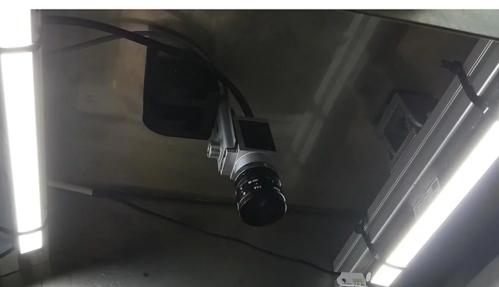 Basler Ace camera with lens used for OCR-based inspection of printed text.