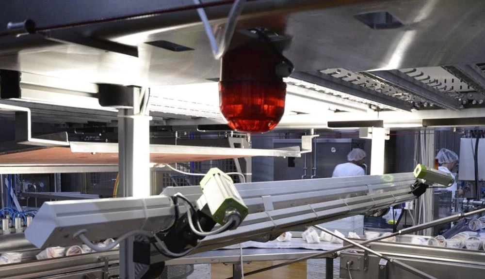 Industrial camera system mounted above a conveyor for real-time ice cream inspection.
