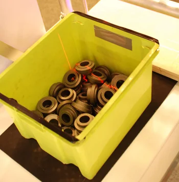 Box with raw metal parts for manufacturing, scanned by machine vision for sorting and inspection.