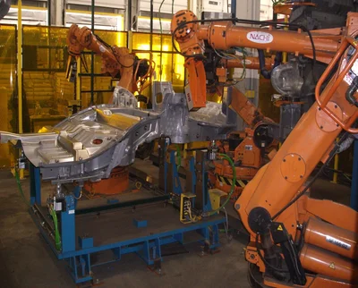 Industrial robots performing a coordinated automated inspection on an automotive part.