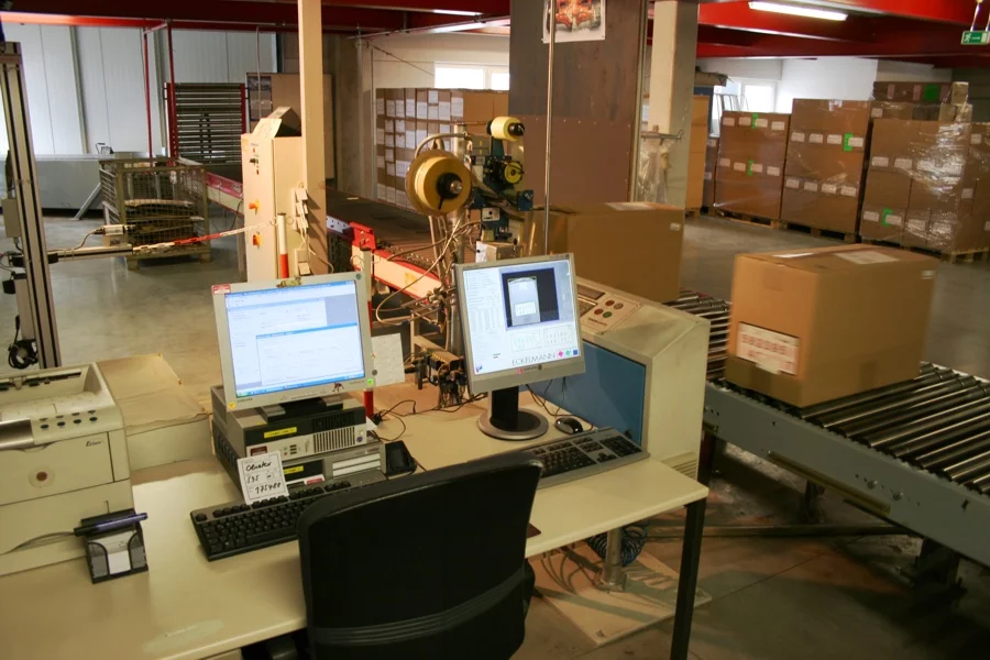 Automated packet identification system with PC, user interface, and labeling machine in a warehouse environment.