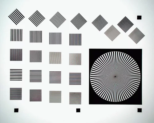 Camera test chart with line patterns and a Siemens star used for measuring resolution, contrast, and optical performance.